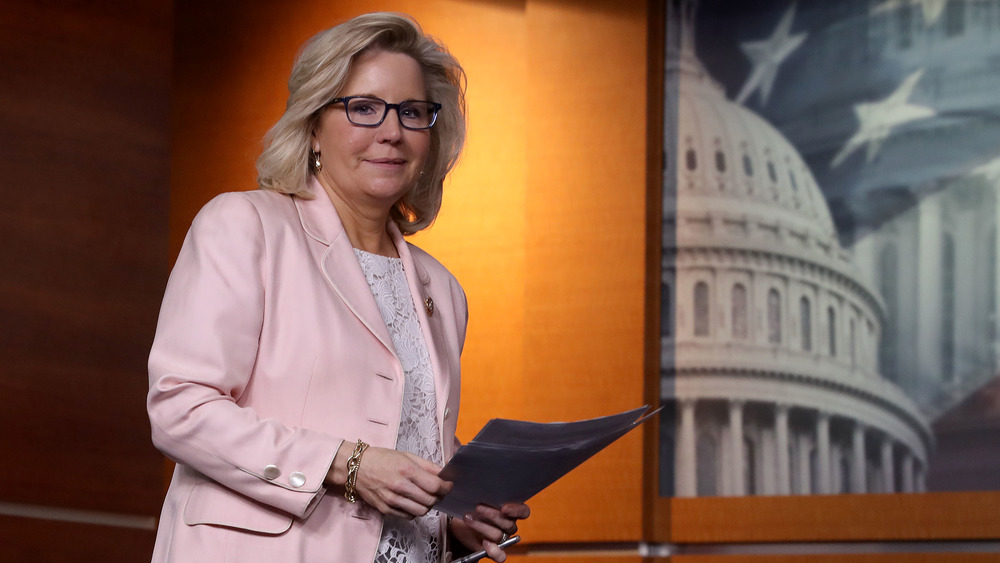 Liz Cheney in pink jacket approaching podium