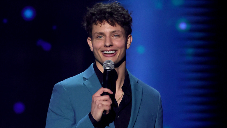 Matt Rife smiling onstage and holding mic