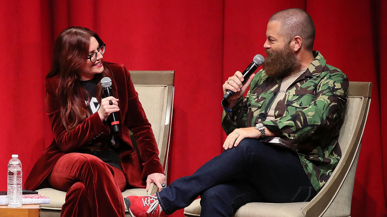 Mullally and Offerman hold microphones and discuss their book in front of a curtain