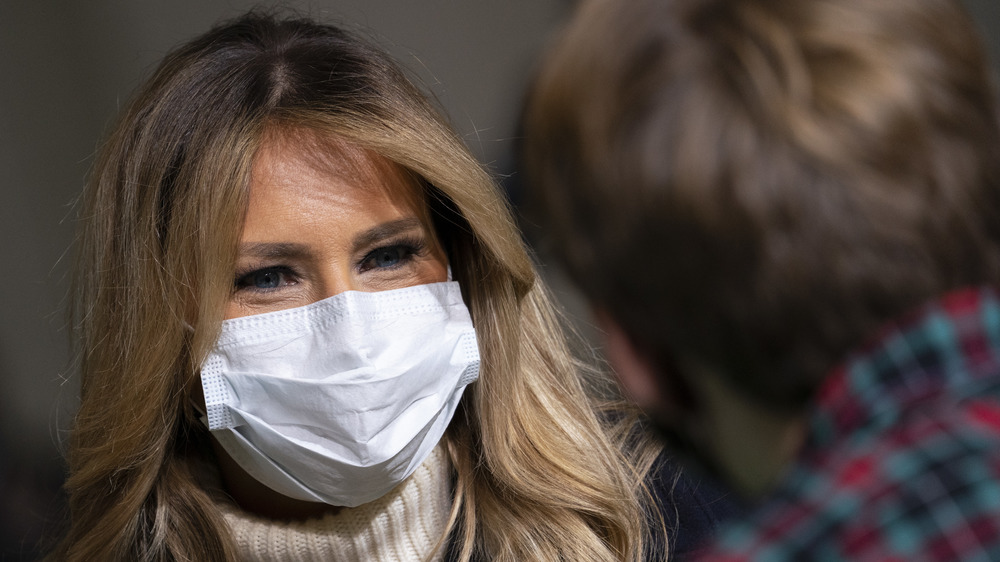 Melania Trump in a mask speaking to a child