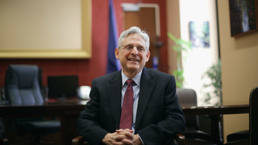 Merrick Garland sitting in chair, smiling