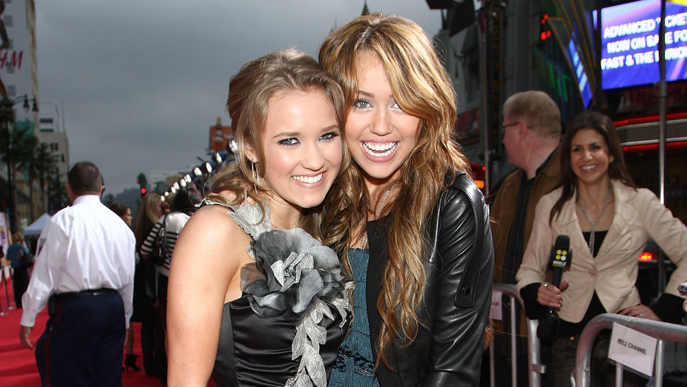 Emily Osment and Miley Cyrus smile