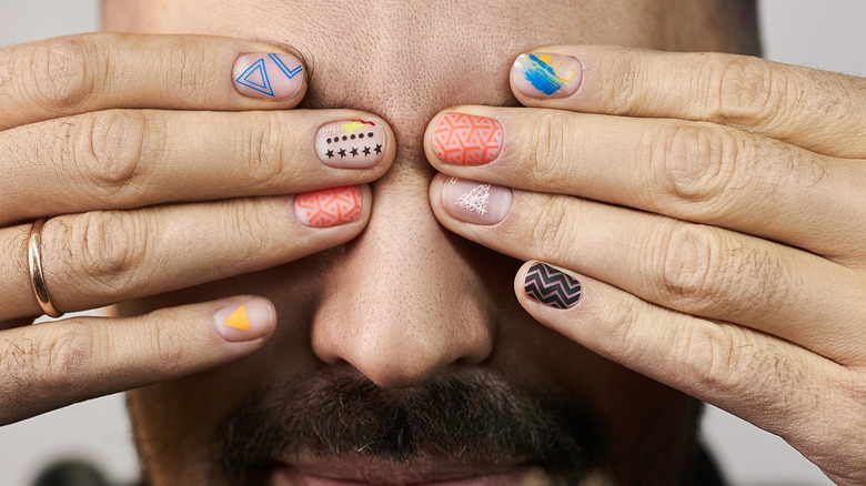 A man covers his eyes with his polished nails