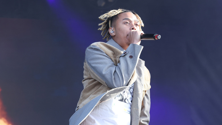 Cordae performing onstage with flames