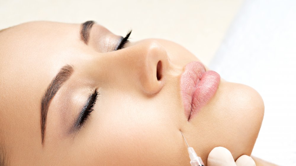 A Botox needle being used beside a woman's mouth 