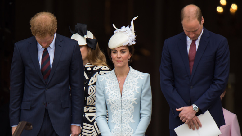 Prince Harry and Prince William looking down with Kate Middleton