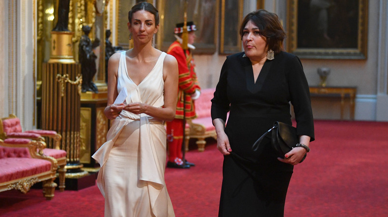 Rose Hanbury & woman walking through palace hall