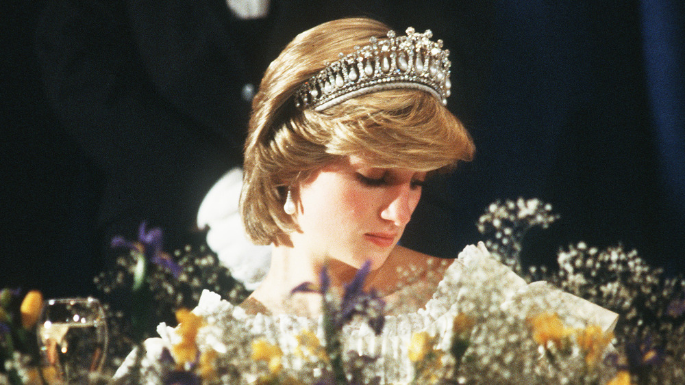 Princess Diana wearing a tiara behind flowers