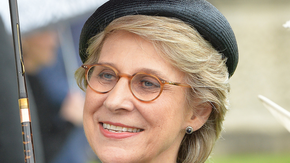 Duchess Birgitte smiling, wearing hat and holding umbrella