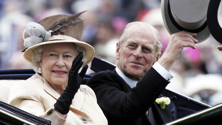 Queen Elizabeth and Prince Philip waving from car