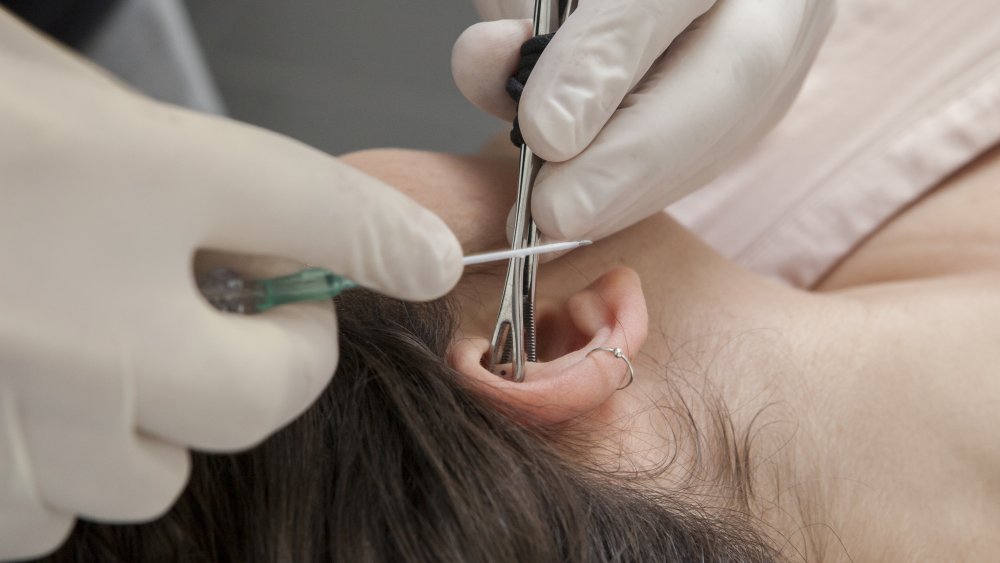 Woman getting her ear pierced 