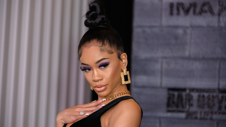 Saweetie exaggerated pose on red carpet with high bun