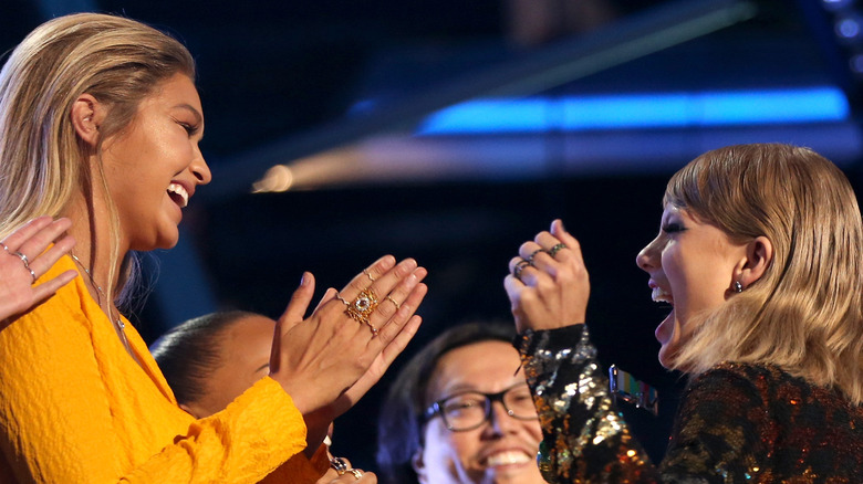 Gigi Hadid and Taylor Swift smiling at each other on stage