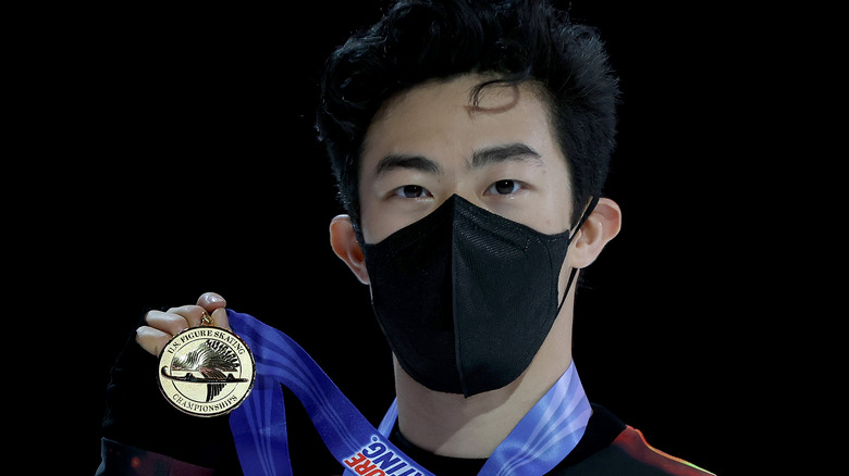 Masked Nathan Chen holding gold medal