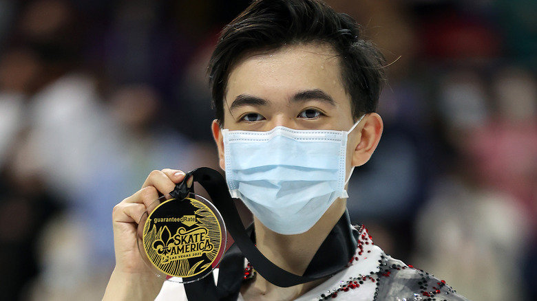 Vincent Zhou in mask holding medal