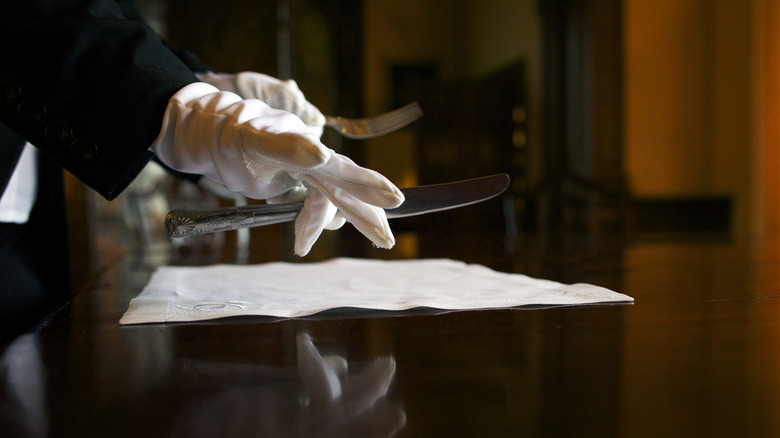 Gloved hand setting a table