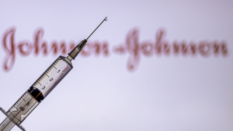 Vaccine syringe in front of Johnson & Johnson sign