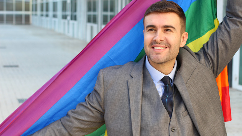 A happy man holds a rainbow flag