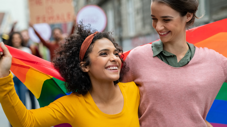 Women walk with pride flag wrapped around them