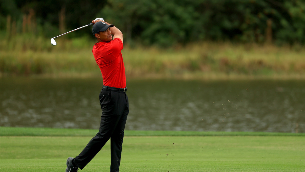 Tiger Woods playing golf in red shirt and baseball hat