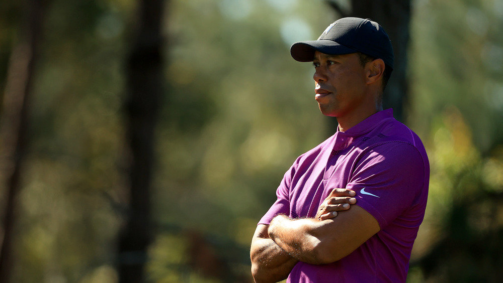 Tiger Woods looking serious with arms crossed in purple polo shirt