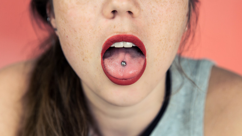 Woman in grey tank top with tongue piercing 