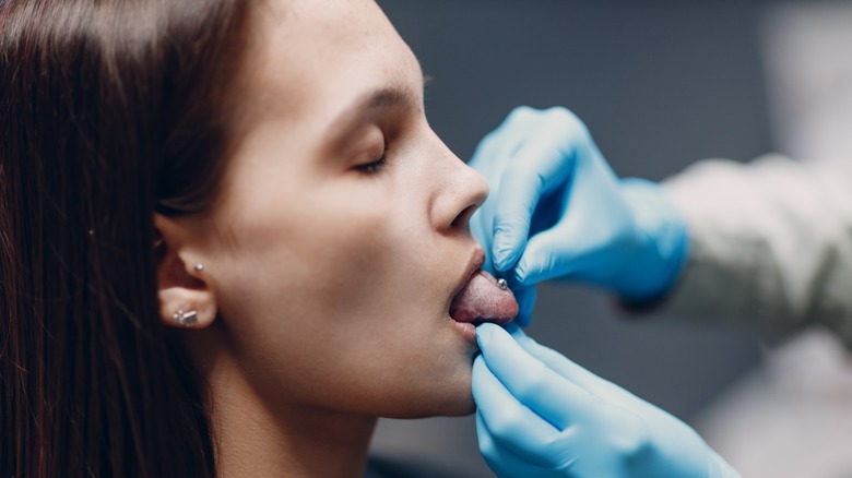 Tongue piercing appointment with rubber gloves