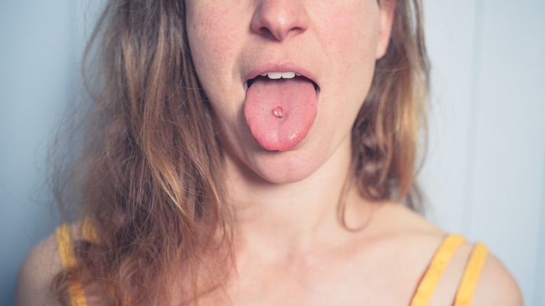 Woman in yellow with clear tongue piercing 