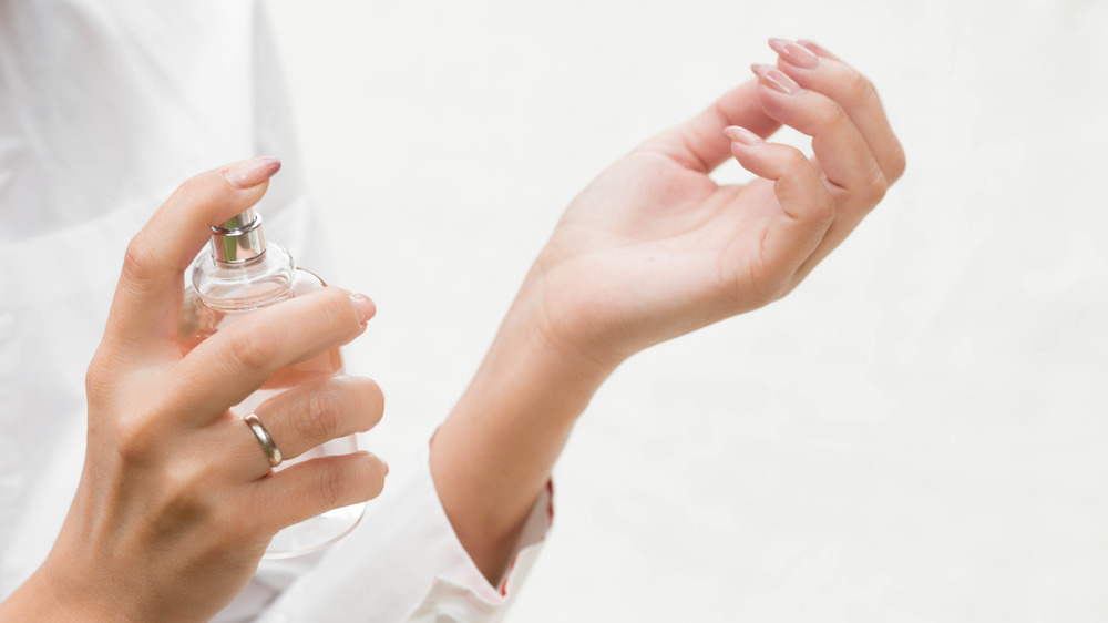 Woman spritzes perfume on wrist