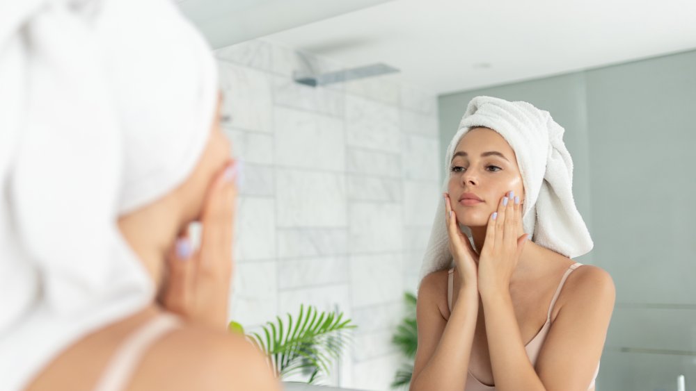 Woman looking at herself in the mirror after a shower 