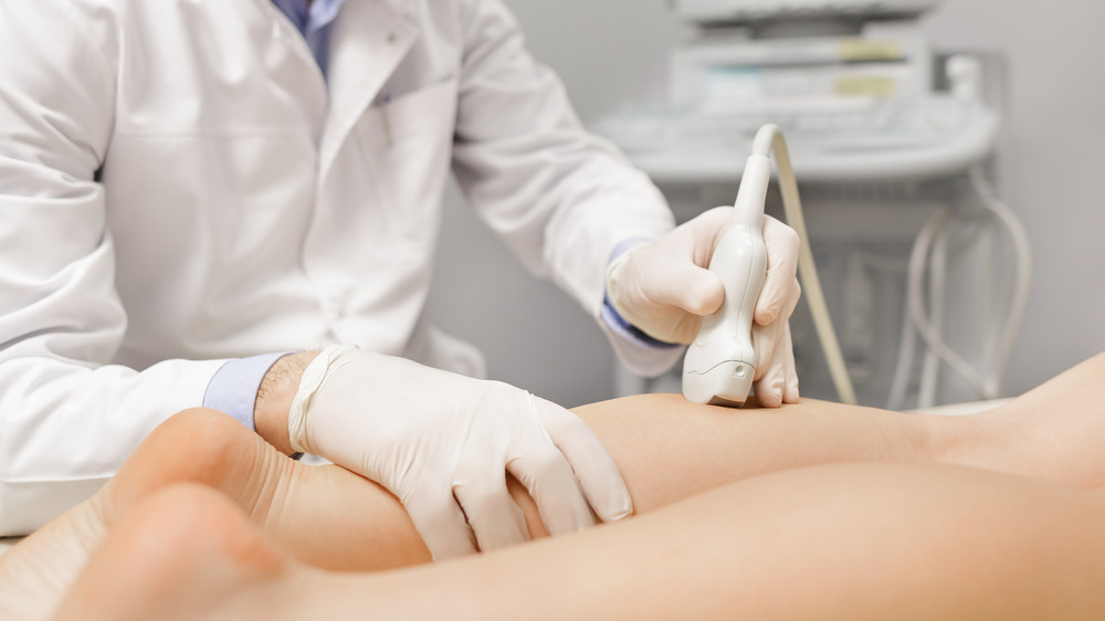 A doctor taking an ultrasound of a person's legs