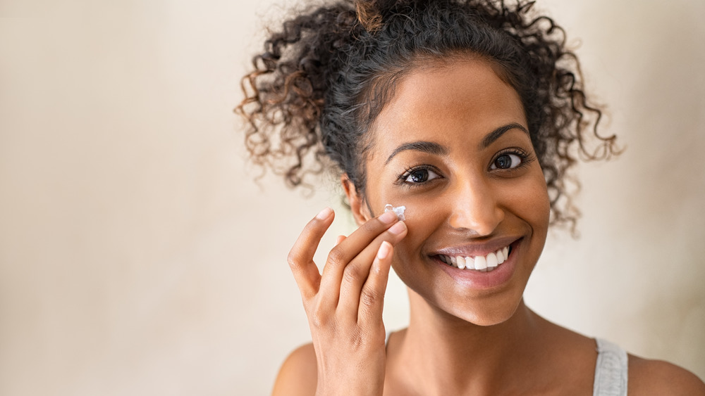 A woman putting lotion on her face