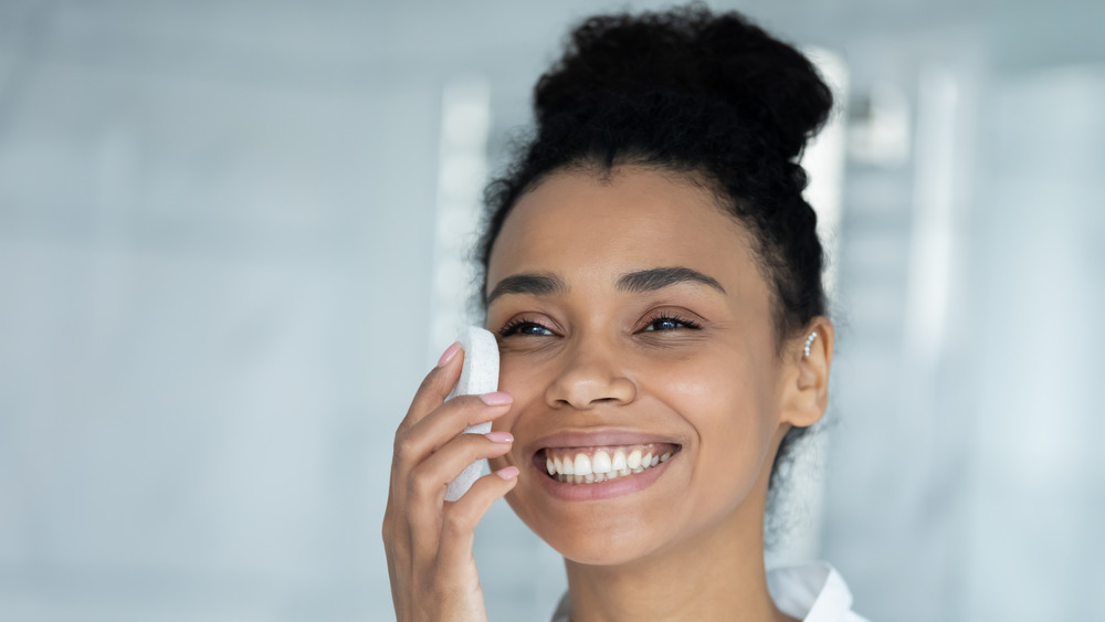 A woman exfoliating her face, smiling