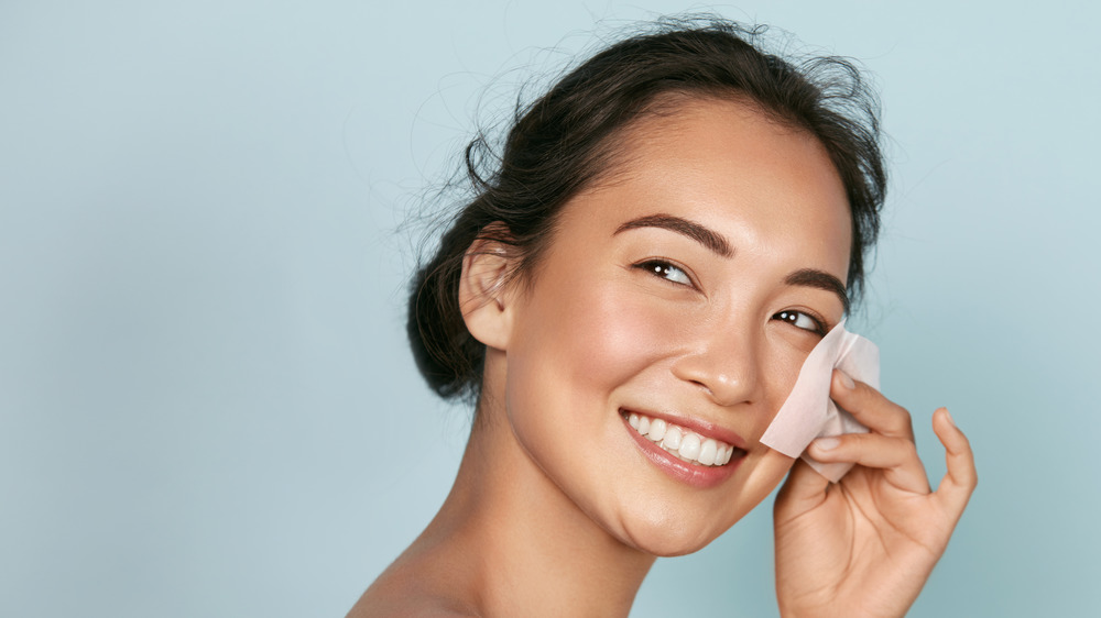 A woman blotting her oily skin