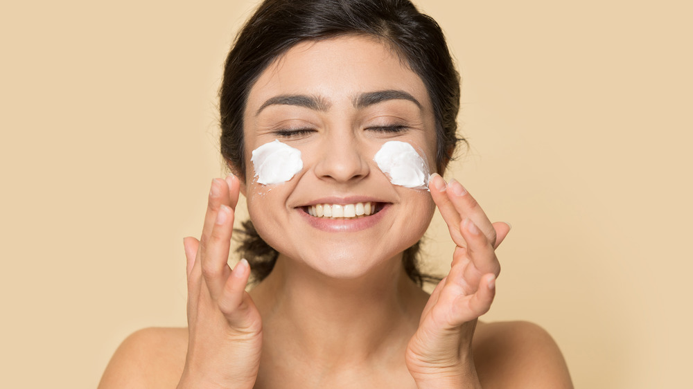 A woman applying face cream