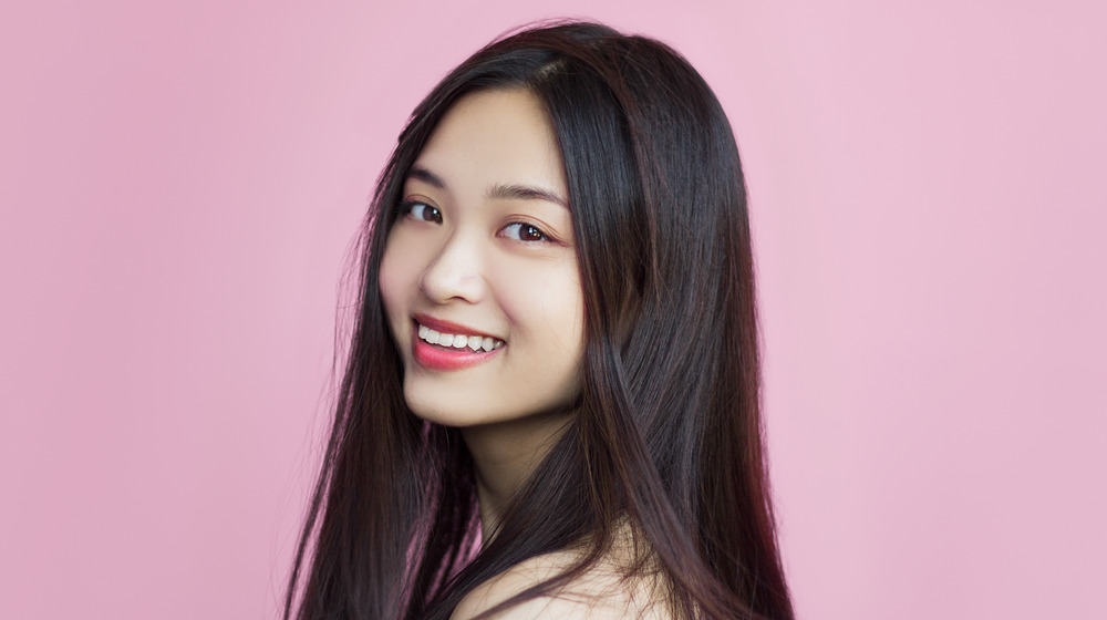 A woman with good skin and long hair, smiling