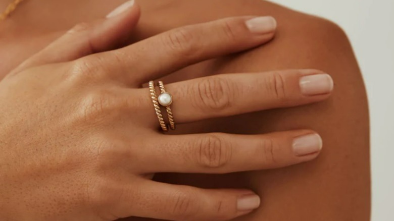 Dark-skin hand with gold and pearl rings