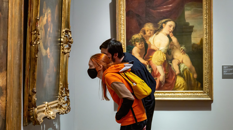 Two people looking at a painting in a museum 