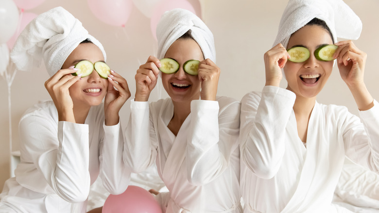 Three women in spa robes with cucumbers over their eyes 