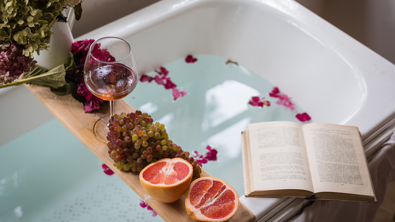A bath tub with wine and flowers 