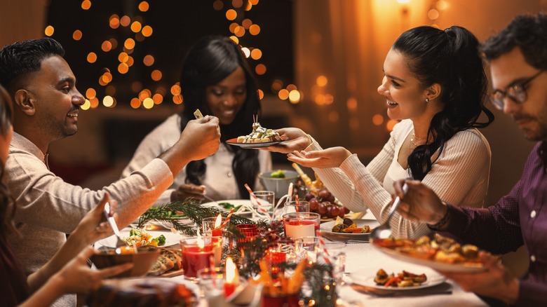 A group of people smiling at a holiday party table 