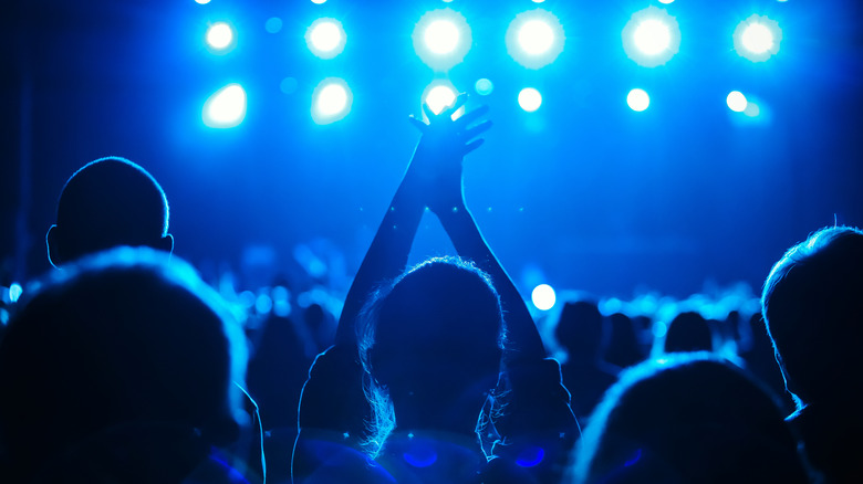 A person with their hands up at a concert 