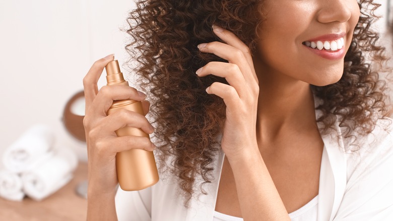 Woman spraying her curly hair with product