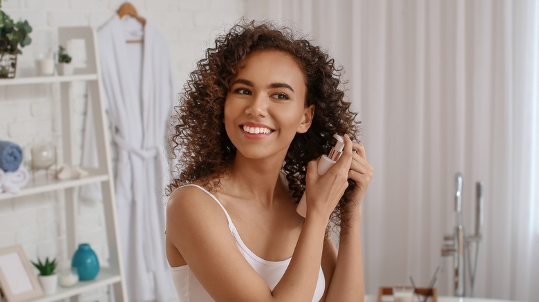 Woman styling her curls with a spray