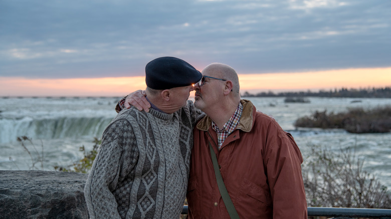 Older gay couple leans in for a kiss