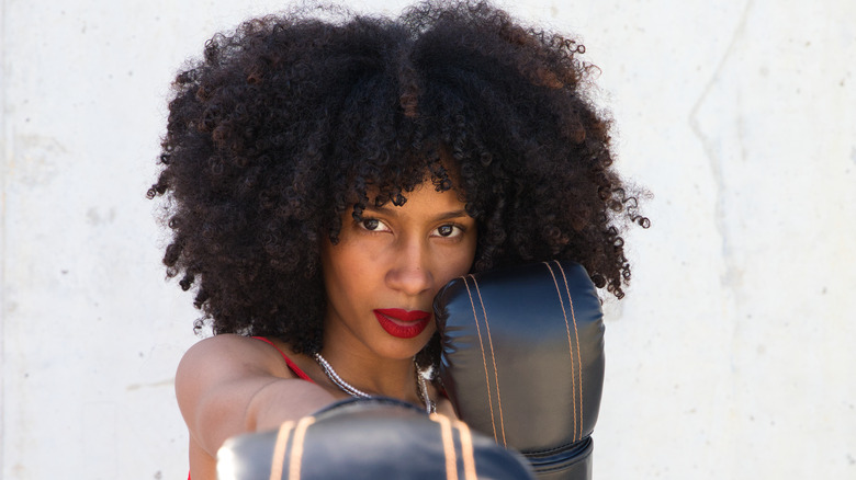 Woman with curly hair and boxing gloves