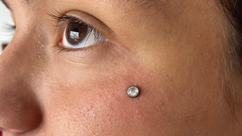 Person with a dermal piercing on face