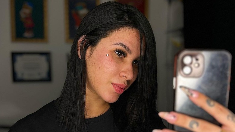 Woman taking selfie with dermal piercing