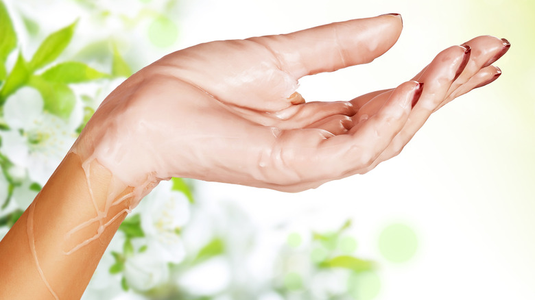 A hand covered in paraffin wax, nails painted red