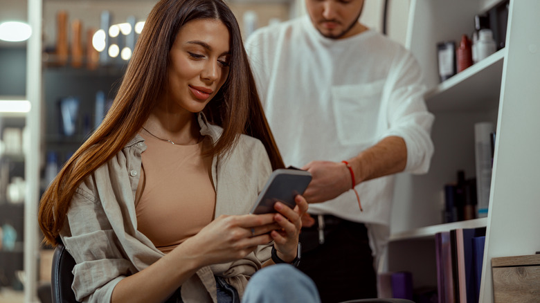 Woman texting while getting haircut